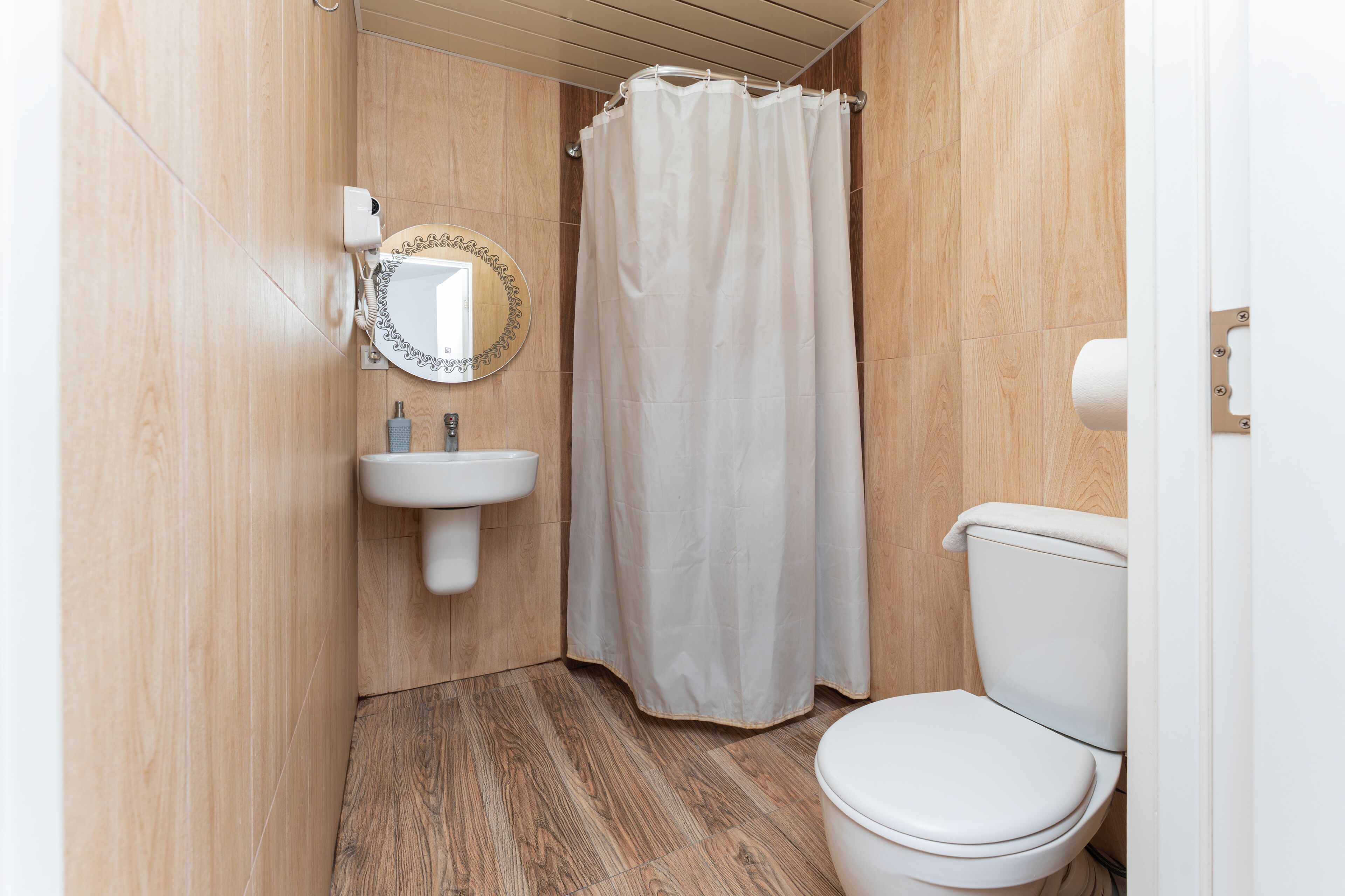 Un baño con inodoro, lavamanos y cortina de ducha.