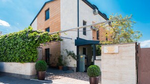 A building with a modern architectural style, featuring a large entrance with a glass door, potted plants, and a signboard. - Alex Hotel (Yerevan)