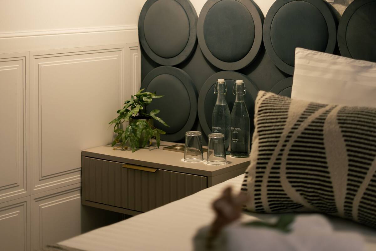 A neatly arranged bedroom with a bed, bedside table, and a hanging lamp.