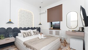 A modern bedroom with a large bed, bedside tables, a desk, a mirror, and a window with a view. - Alex Hotel (Yerevan)