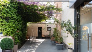 An outdoor patio area with tables and chairs, potted plants, and a building entrance with a 'Coffee' sign. - Alex Hotel (Yerevan)