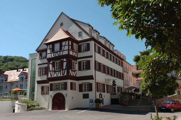 Un edificio tradicional con entramado de madera, con una puerta roja, varias ventanas y una escalera que lleva a la entrada.