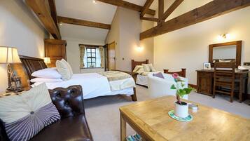 A bedroom with two beds, a wooden table, a leather couch, and a dresser.