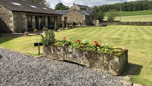 A stone building with a lawn, potted plants, and a gravel path. - GreenGrove Country House B&B (Skipton)