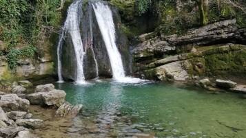 A waterfall in a natural setting with clear water and surrounding rocks.