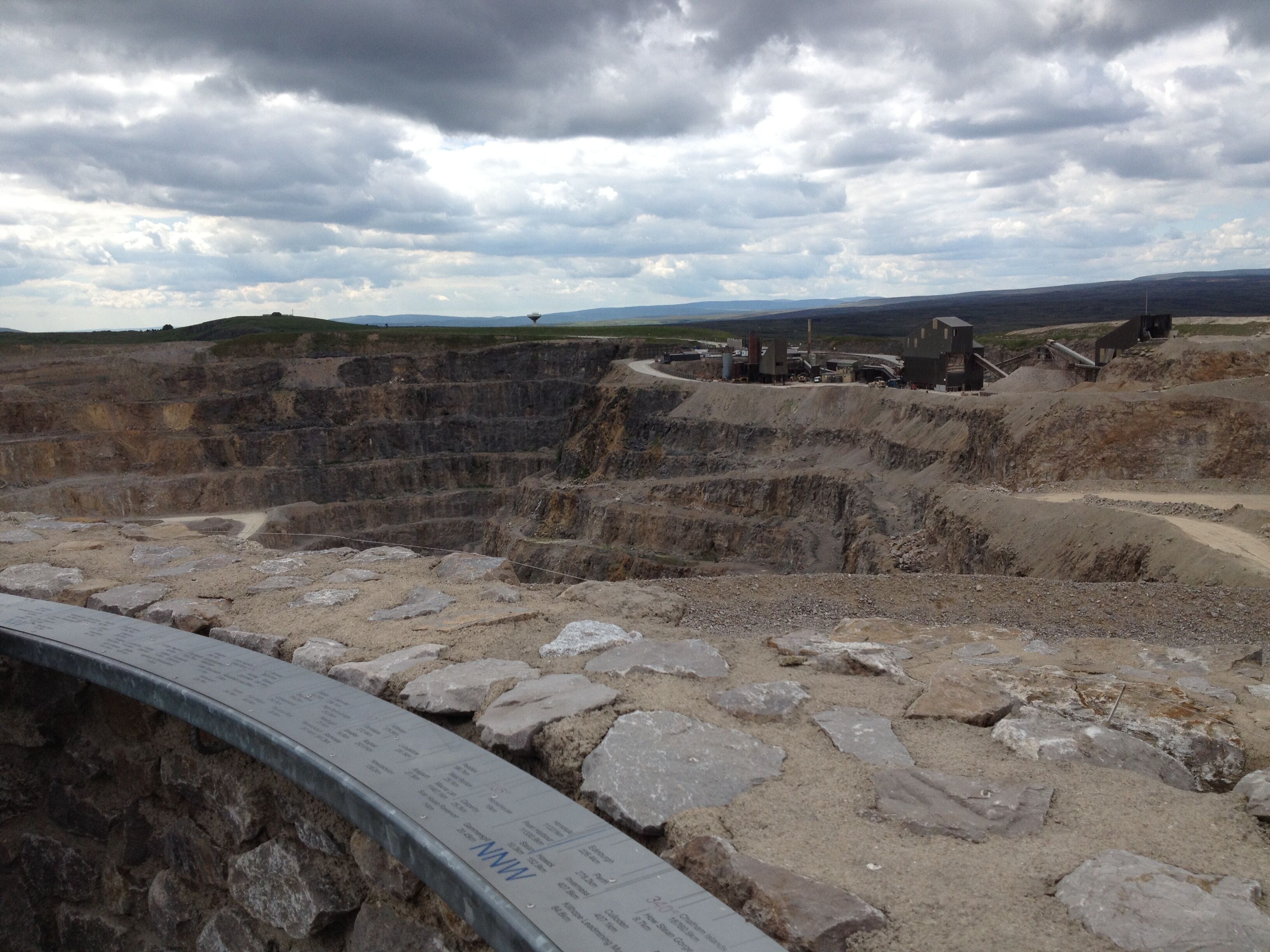 A large open excavation site with a curved metal barrier in the foreground.