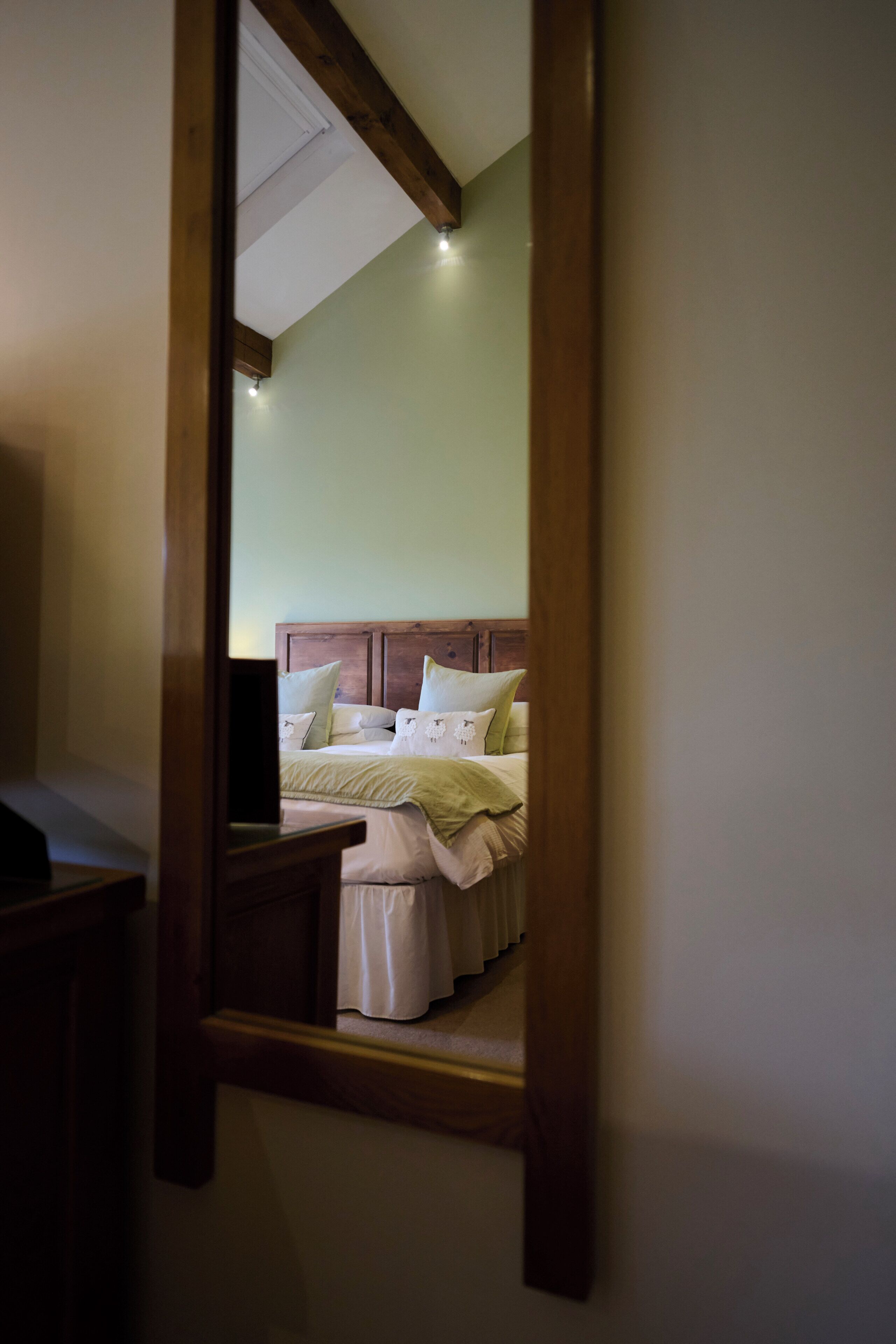 Een slaapkamer met een houten hoofdeinde, een bed met wit beddengoed en een nachtkastje.