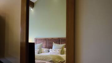Een slaapkamer met een houten hoofdeinde, een bed met wit beddengoed en een nachtkastje.