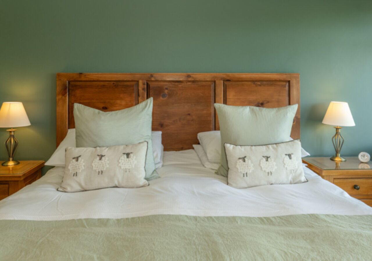 A neatly made bed with two pillows, a wooden headboard, and bedside lamps on either side.