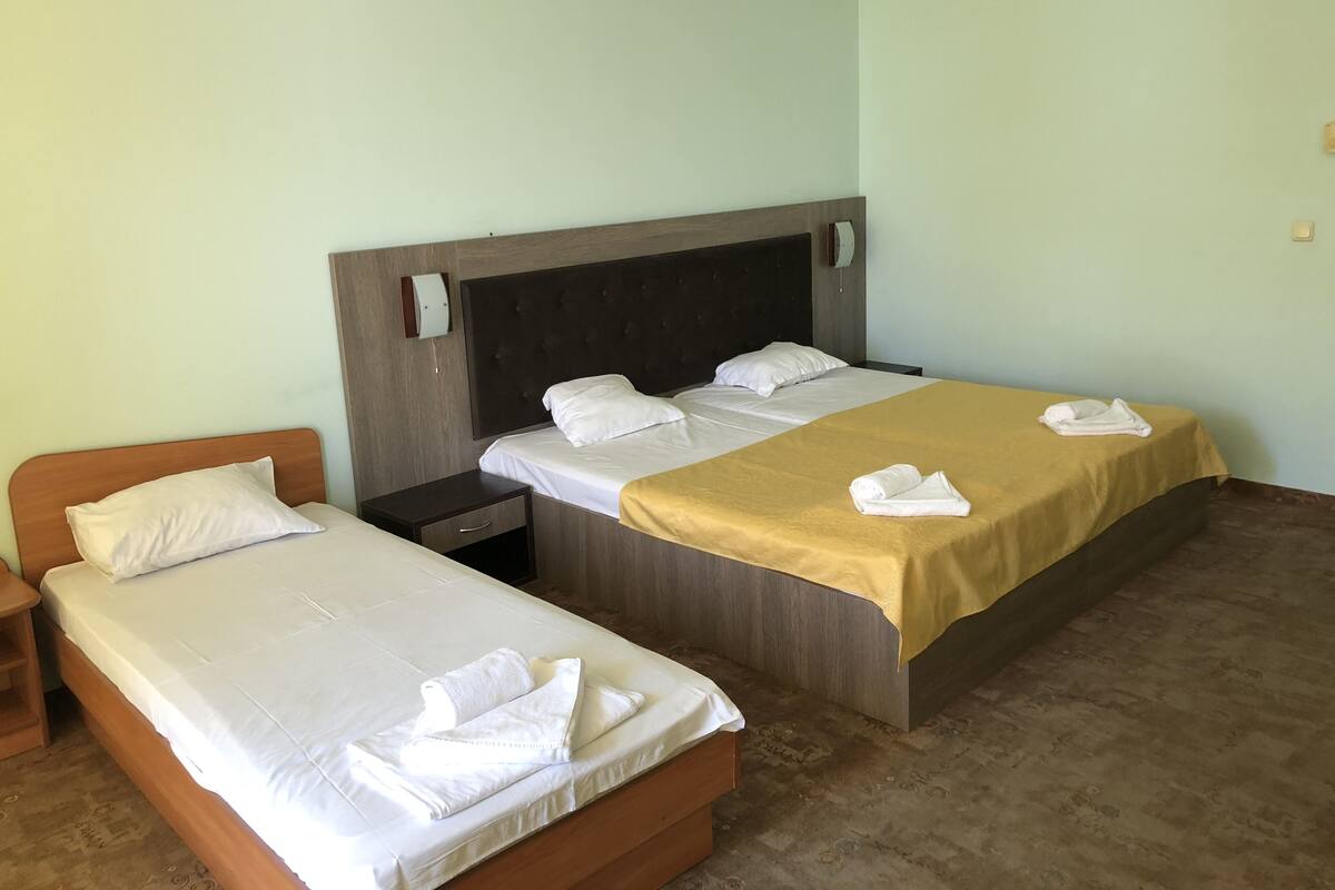 A hotel room with two single beds, a wooden headboard, a bedside table, and a nightstand.