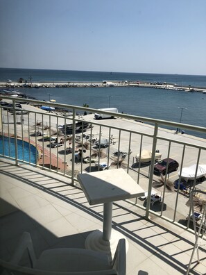 Un balcon avec vue sur un port de plaisance, une piscine et des véhicules garés.