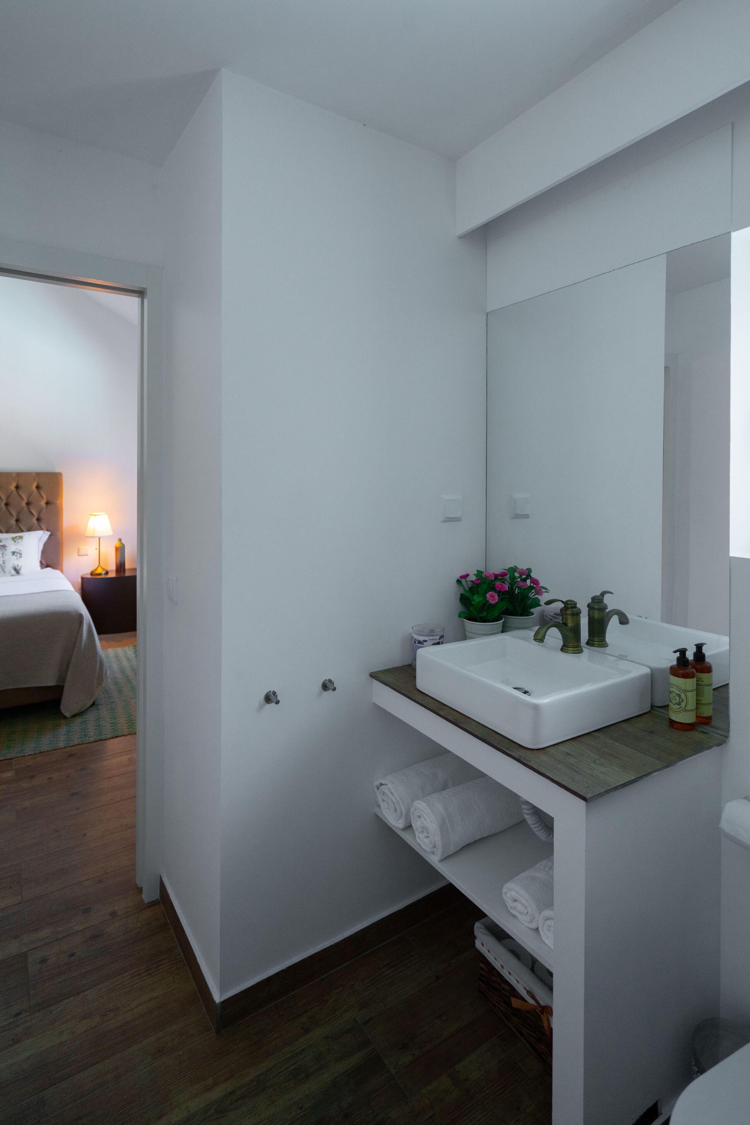 Een moderne badkamer met een witte wasbak, spiegel en een houten aanrechtblad.
