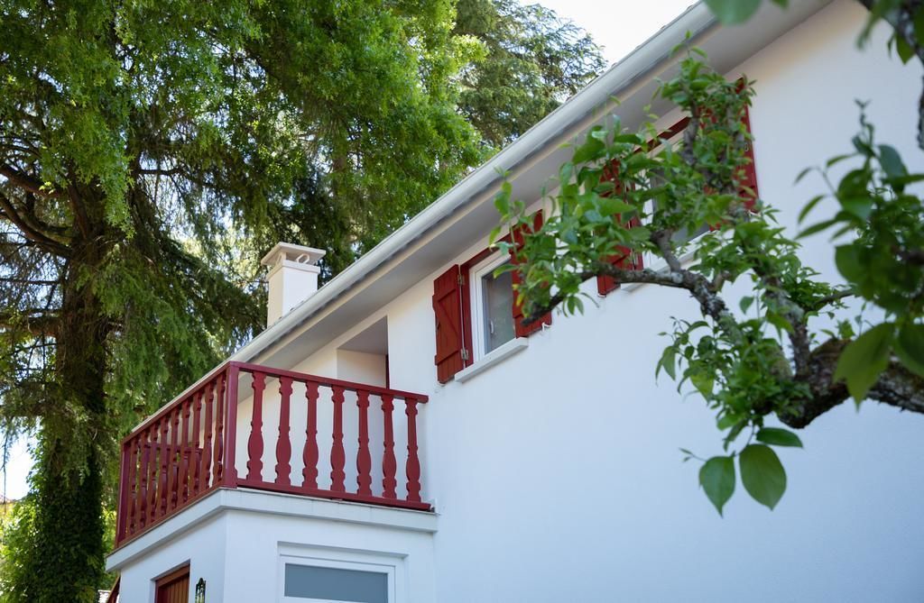 Un edificio blanco con un balcón rojo y una ventana con persianas rojas.