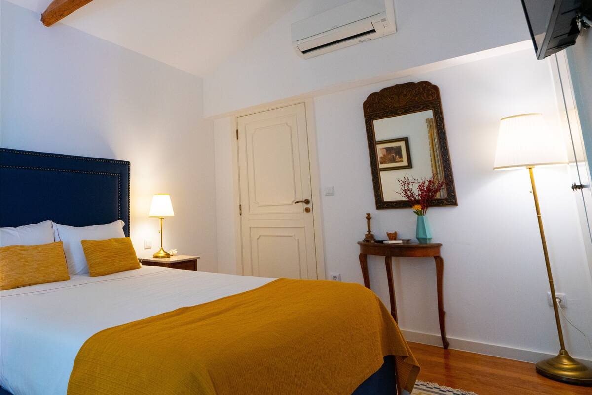 Une chambre d’hôtel comprenant un lit, une table de chevet, une commode, un miroir, une lampe et un téléviseur.