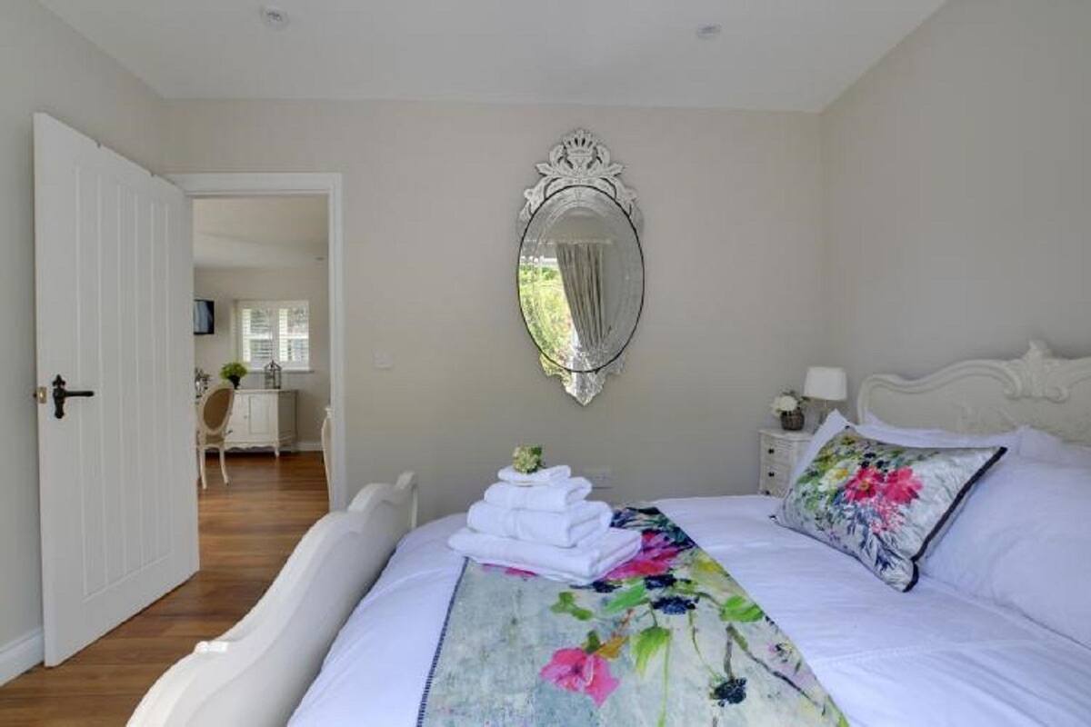 A bedroom with a bed, a mirror, and a view of a dining area.