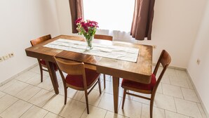 A dining table with a vase of flowers, red cushioned chairs, and a white table runner. - Central Retro Apartment (Prague)