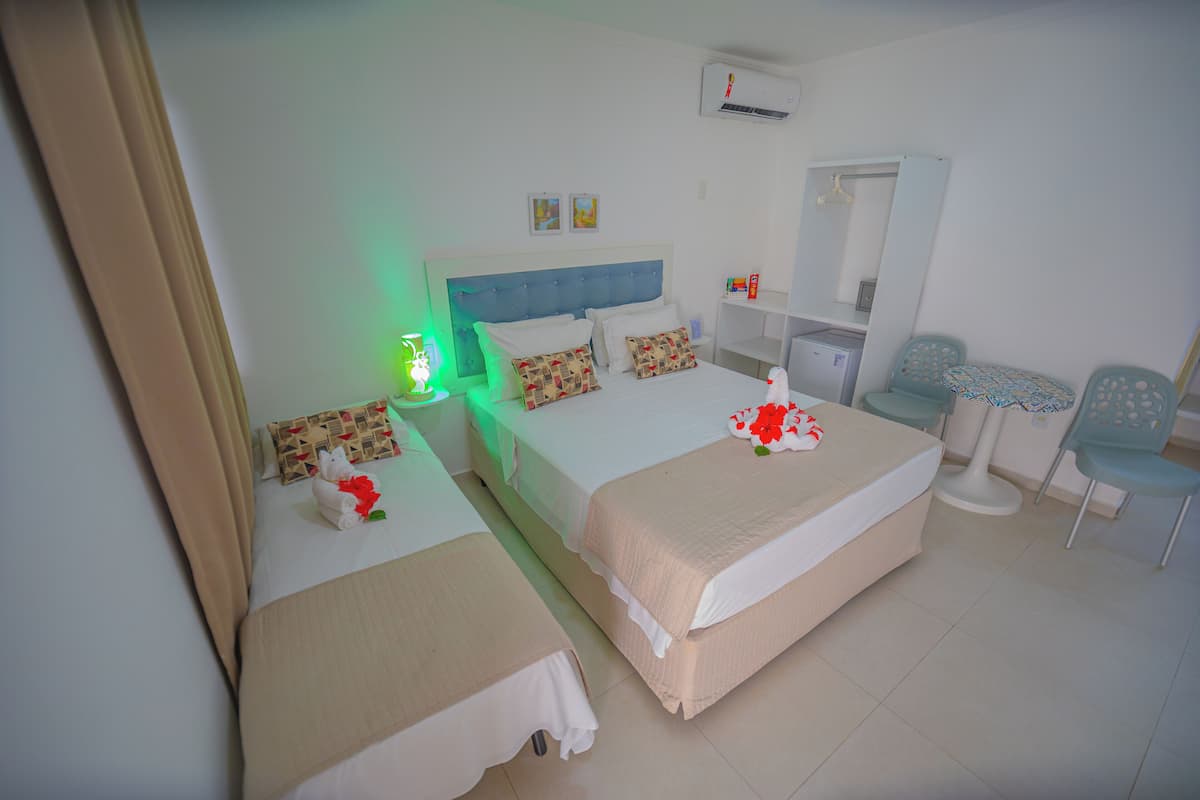 A hotel room with two beds, a desk, a chair, and a mirror.