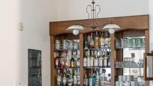 A bar area with a wooden counter, shelves of bottles, glasses, and a cash register.