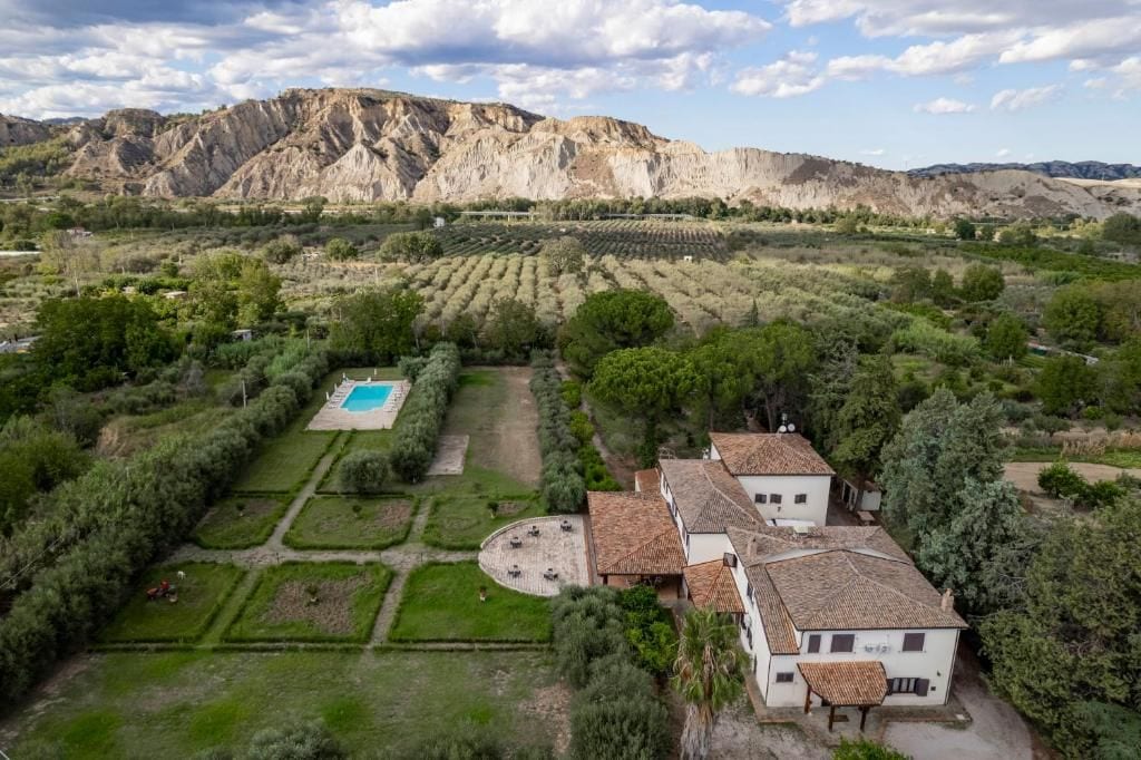 Une villa avec piscine, entourée de jardins en terrasses et dominée par un paysage montagneux.