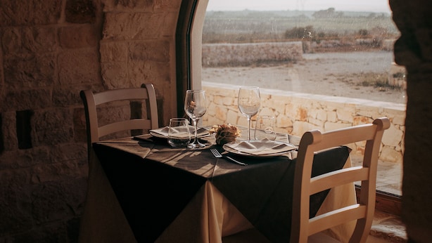A table set for two with a view of a coastal landscape through a window.