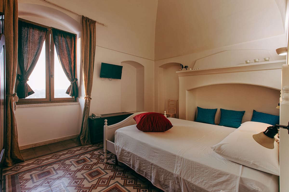 Een hotelkamer met een bed, een televisie, een bureau en een vloer met een patroon.