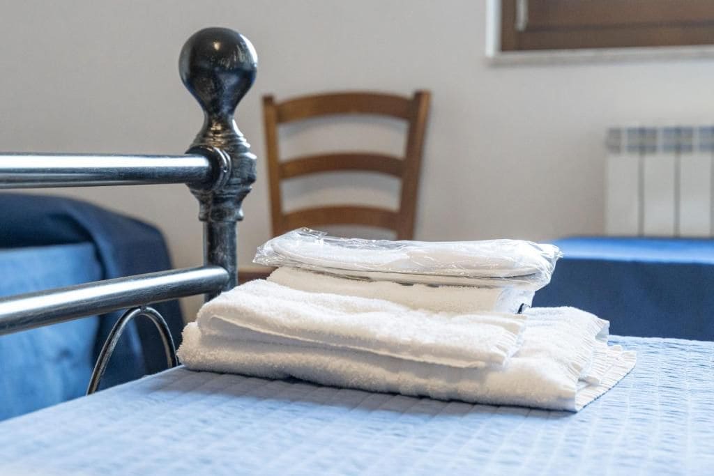 Una cama con cabecera de metal, una silla de madera y un mantel azul.