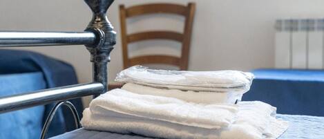 Una cama con cabecera de metal, una silla de madera y un mantel azul.
