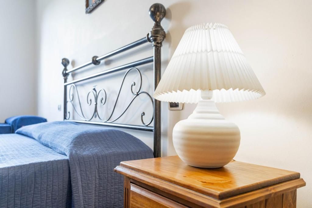 A bed with a headboard, a bedside table with a lamp, and a blue bedspread.