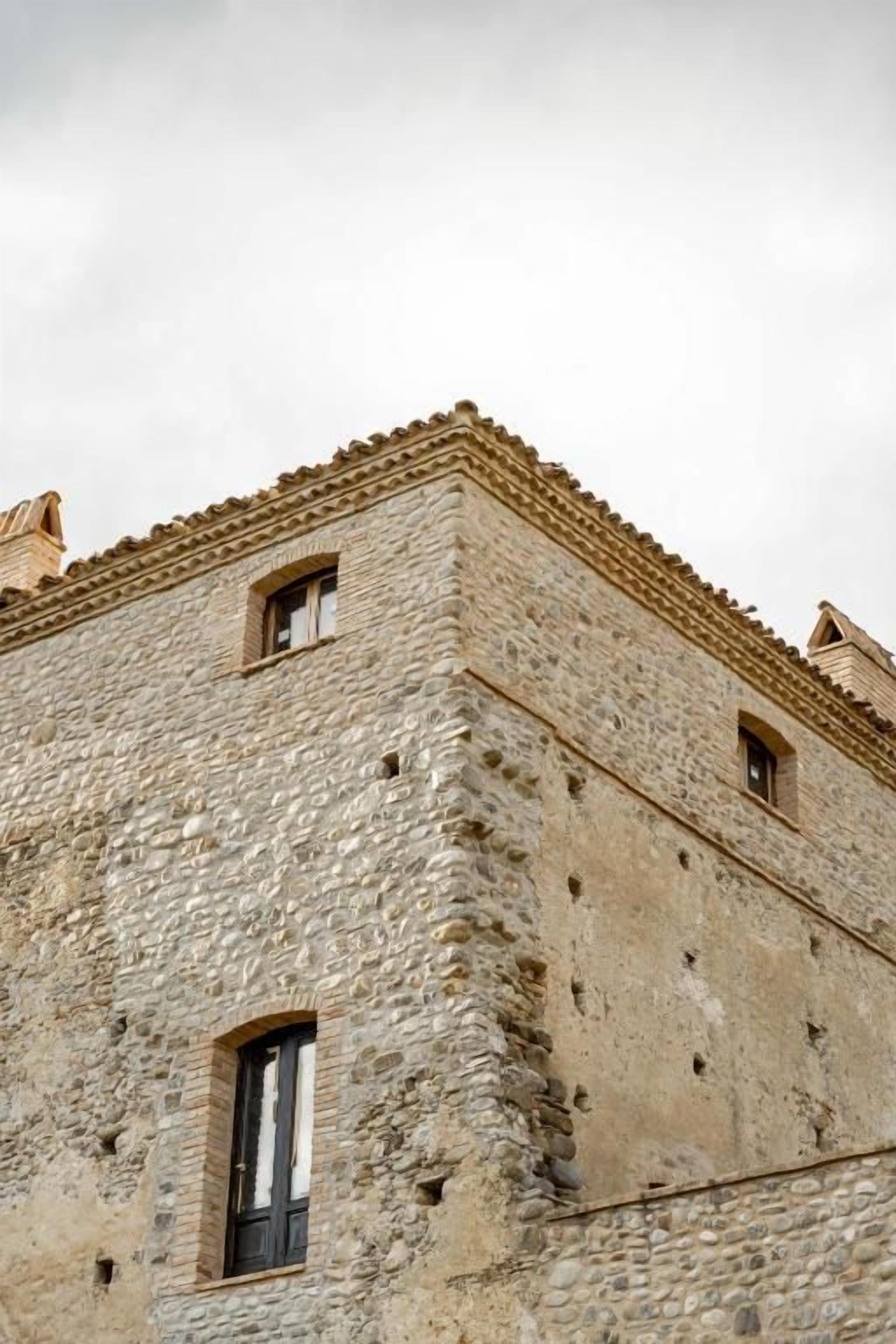 Un edificio de piedra con techo plano y ventanas pequeñas.