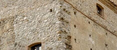 Un edificio de piedra con techo plano y ventanas pequeñas.