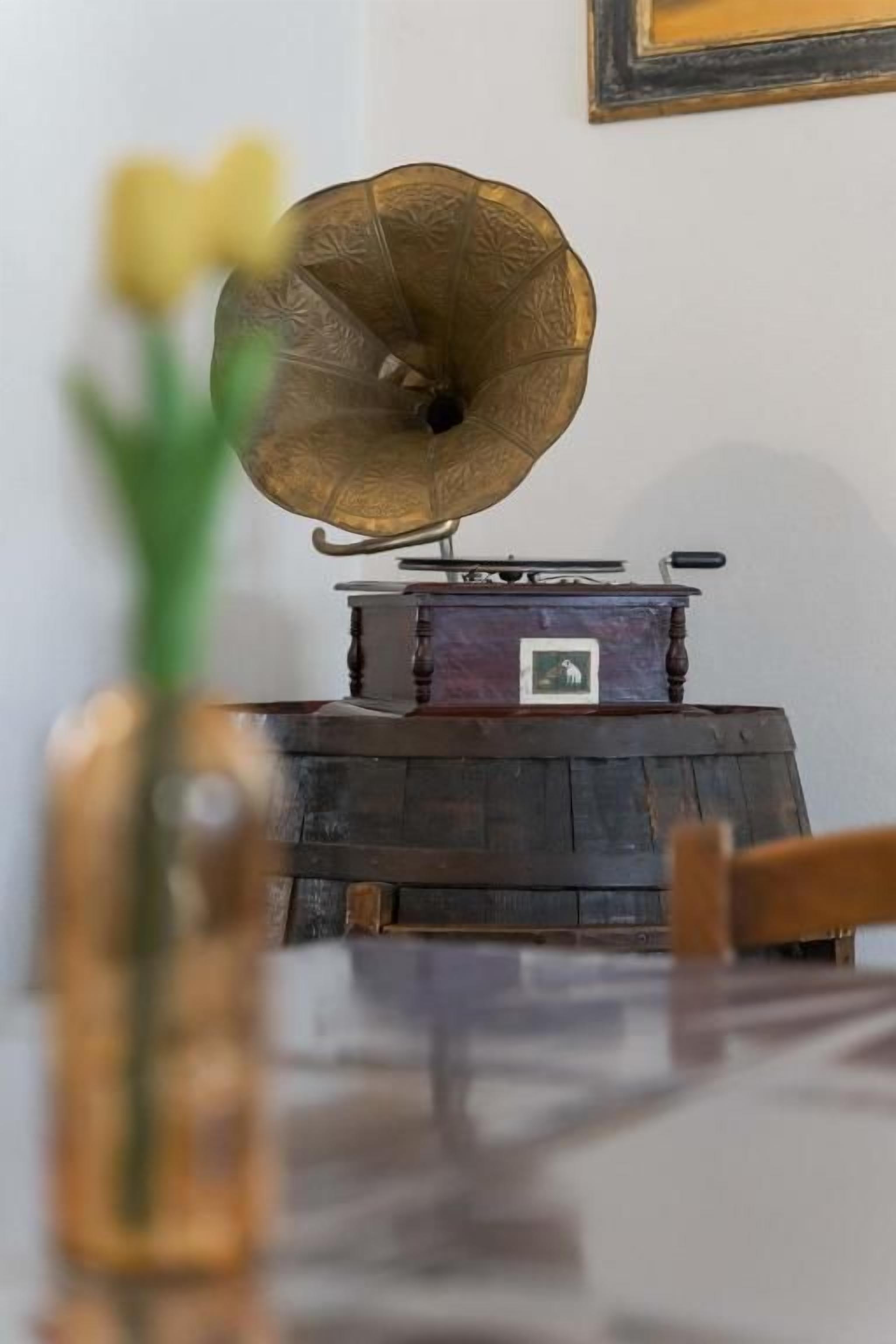 Un tocadiscos antiguo sobre una mesa de madera, con un jarrón de flores amarillas en primer plano.
