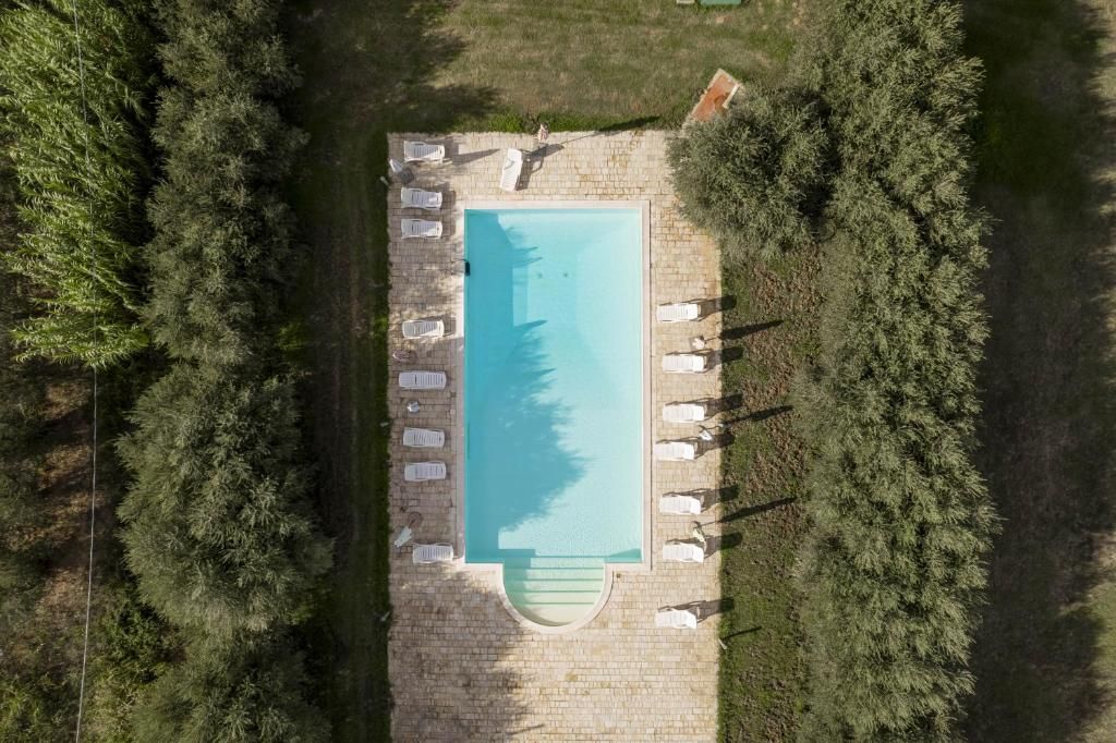 Vista aérea de una piscina rectangular rodeada de sillas de descanso y una terraza de piedra.