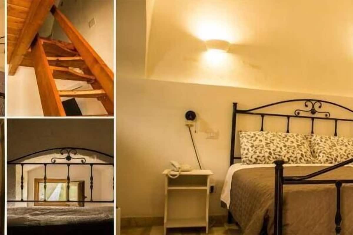 Een slaapkamer met een bed, nachtkastje, spiegel en een trap.
