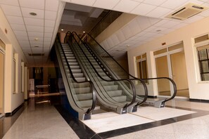 An indoor escalator in a building with a tiled floor and a ceiling with recessed lighting. - Statement Hotel (Abuja)