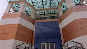 Um edifício moderno com entrada em vidro e fachada geométrica.