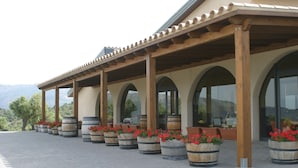 Un espacio al aire libre cubierto con columnas y arcos de madera, plantas en macetas y vistas a las montañas.