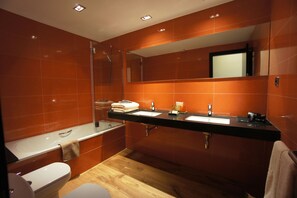 Un baño moderno con un espejo grande, dos lavamanos, una bañera y un inodoro.