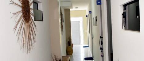 Un pasillo con un banco, un adorno de pared y una planta en maceta.