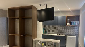 A compact kitchen with a built-in microwave, a small refrigerator, and a dining area with a table and chairs. - Pousada Marbello (Maragogi)