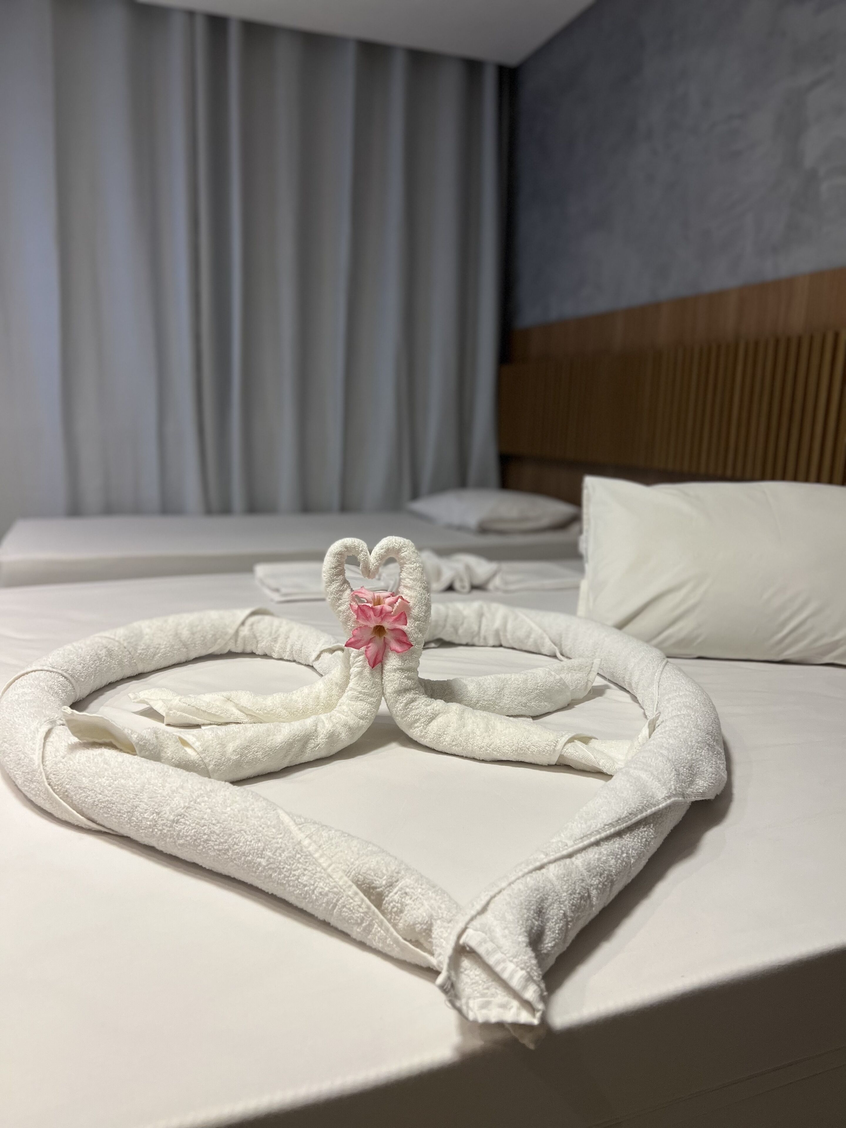 Une chambre d’hôtel avec un lit bien fait, une tête de lit en bois et une grande fenêtre avec des rideaux.