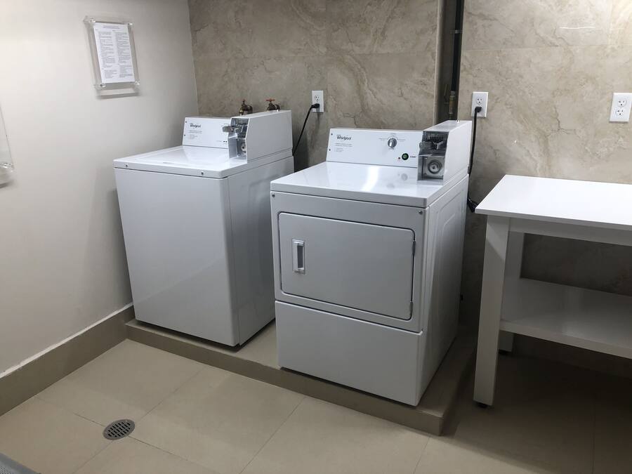 A laundry room with two Whirlpool washers and a table.
