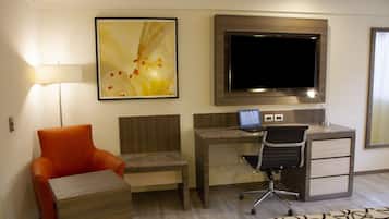 Ein Hotelzimmer mit Schreibtisch, Stuhl, Fernseher und Lampe.