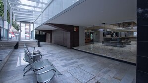 Un espacio interior amplio con techo de cristal, una zona de estar con sillas y una barra con un cartel.