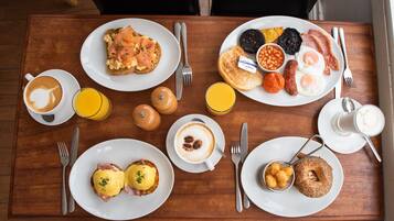 A breakfast table with plates of eggs, toast, beans, and sausages.