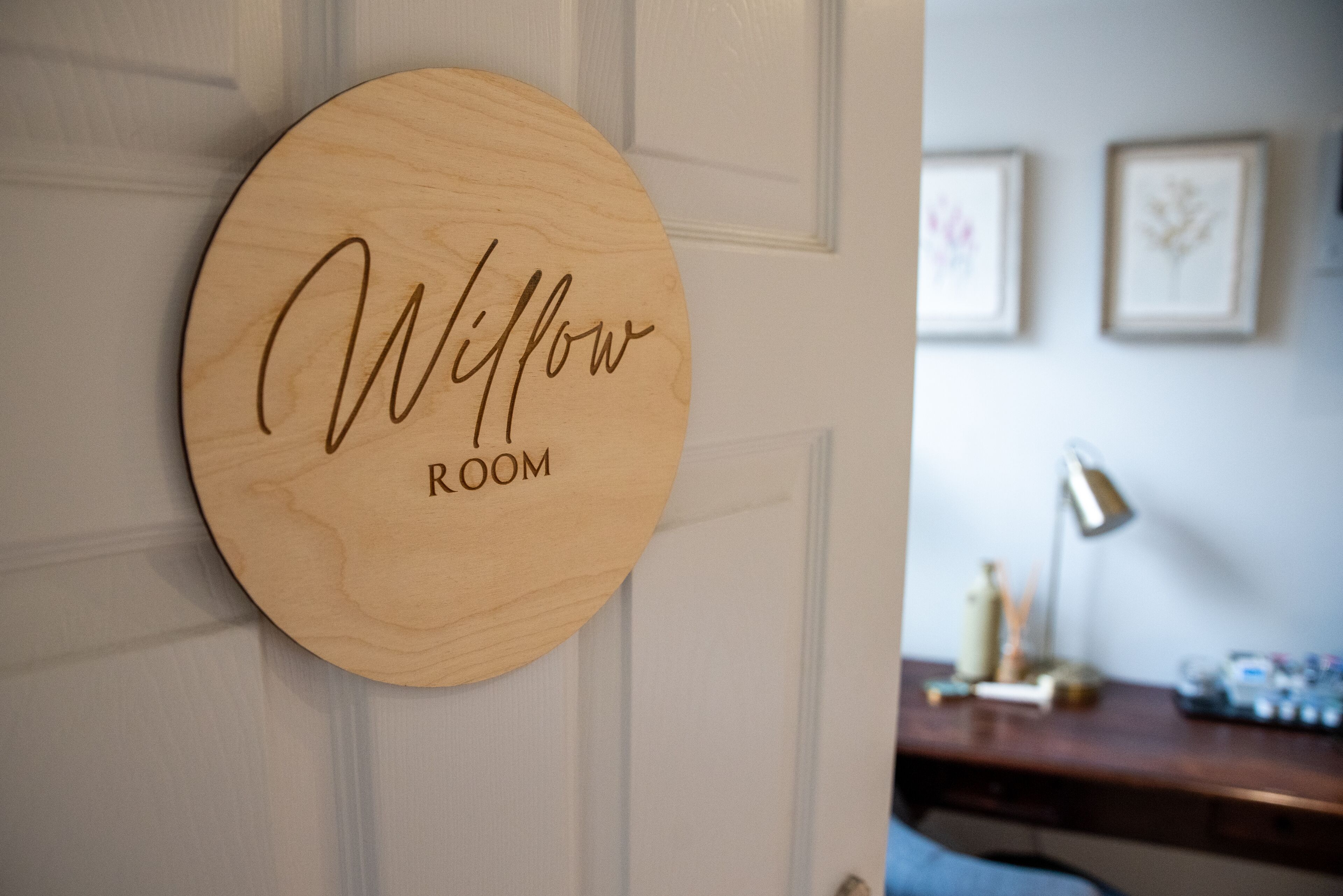 A wooden sign with "Willow Room" written on it, mounted on a door.