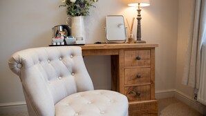 A tufted armchair, a wooden desk with drawers, a lamp, a coffee maker, and a vase with flowers. - The Family Tree (Matlock)