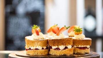 Vier kleine Sandwiches mit Creme und Erdbeeren auf einem Holzboden.