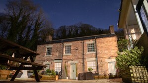 A stone building with a pub sign, outdoor seating, and a clear night sky. - The Family Tree (Matlock)
