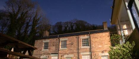 A stone building with a pub sign, outdoor seating, and a clear night sky.