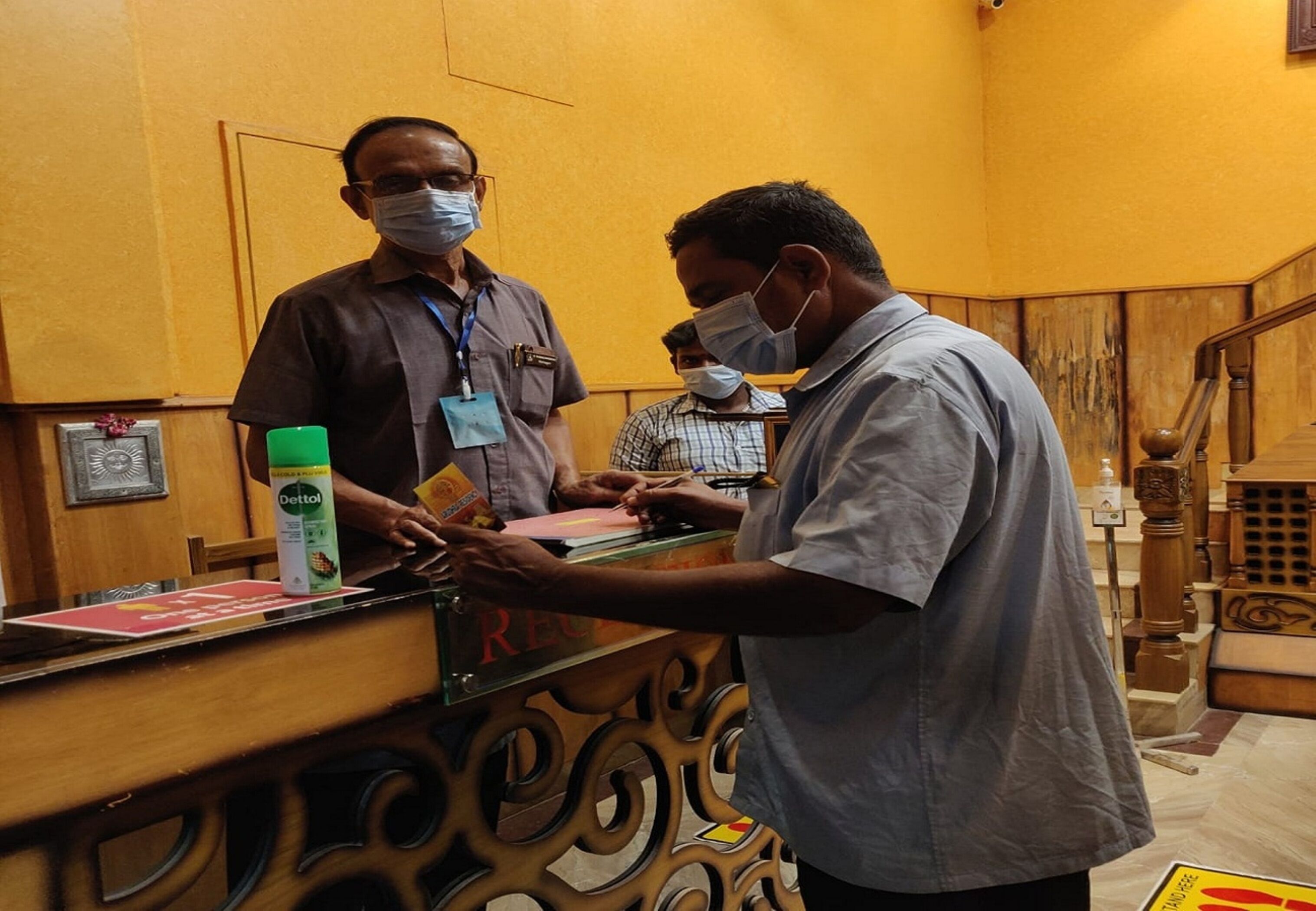 Un comptoir d’accueil où un homme tend une carte à un autre.